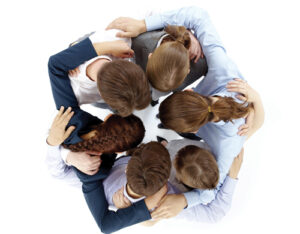 Above view of several business partners nodding heads and embracing each other standing in circle